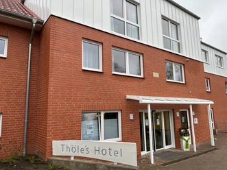 Bakstenen gevel van Thöle's hotel met grote ramen en een overdekte ingang in Vilsen.