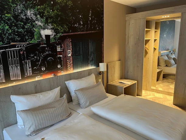 Cozy hotel room with two large beds, wooden furniture and steam locomotive photo wallpaper on the wall.