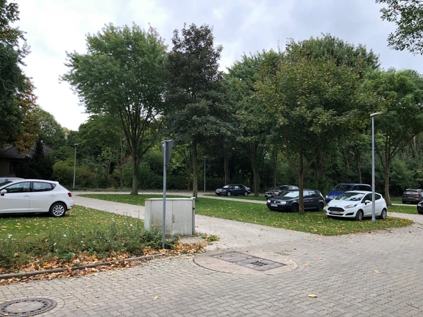 Wohnmobilstellplatz Bücken Wohnmobilstellplatz umgeben von Bäumen, mit geparkten Autos und gepflasterten Wegen im Grünen.