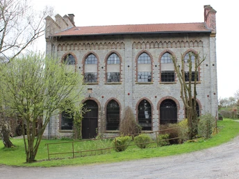Brincker Mühle.jpg Altes Backsteingebäude mit gotischen Fenstern, umgeben von grüner Landschaft und Bäumen.