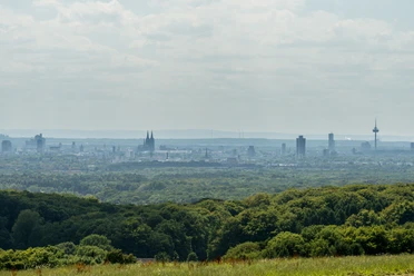 Odenthal Panoramablick auf Kölns Skyline mit Dom, umgeben von grünen Wäldern und sanften Hügeln im Vordergrund.