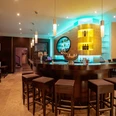 Bar.jpg Moderne Hotelbar mit stimmungsvollem Licht, dunklen Holzverkleidungen und gepolsterten Barhockern.