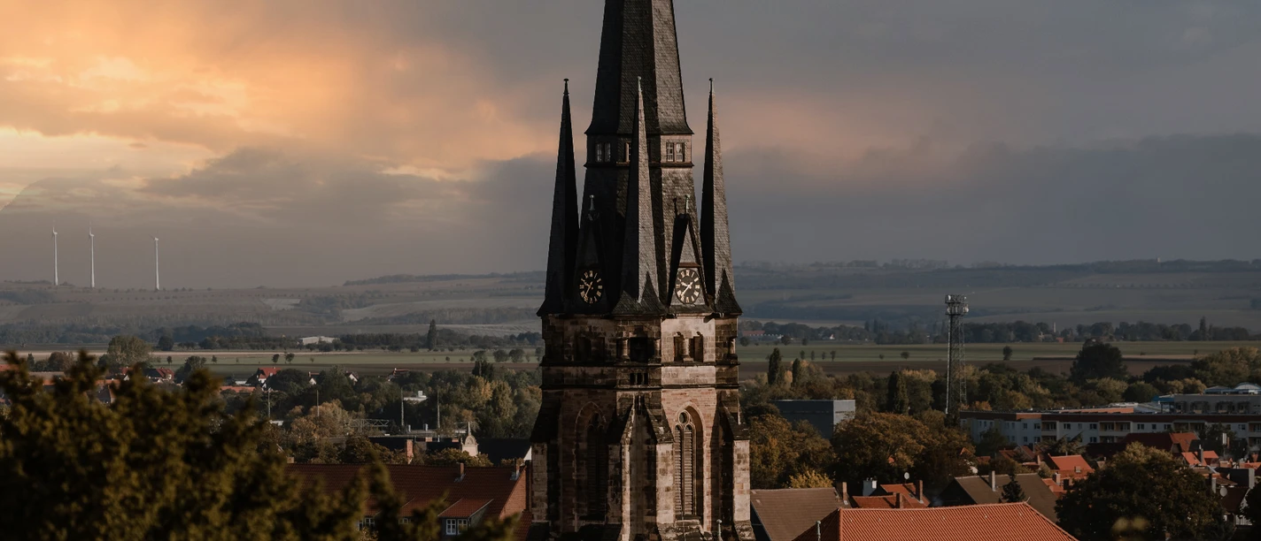 Konzerthaus Liebfrauen WR Spitzer Kirchturm über roten Dächern vor weiter Landschaft und dramatischem Abendhimmel.