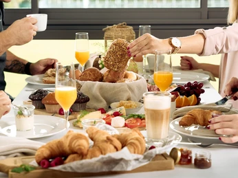 Ansicht Frühstücksbuffet Frühstückstisch mit Croissants, Brötchen, Kaffee, Orangensaft und verschiedenen Aufstrichen.