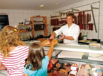 Metzger reicht Mädchen Ahle Wurscht - © Gutes aus Waldhessen e.V.
