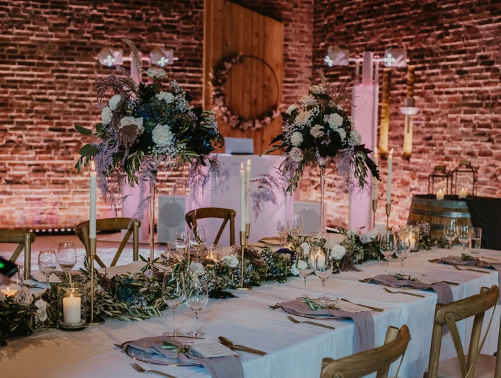 Festscheune Ein festlich gedeckter Tisch in einer Scheune mit stimmungsvoller Beleuchtung und floralen Dekorationen.