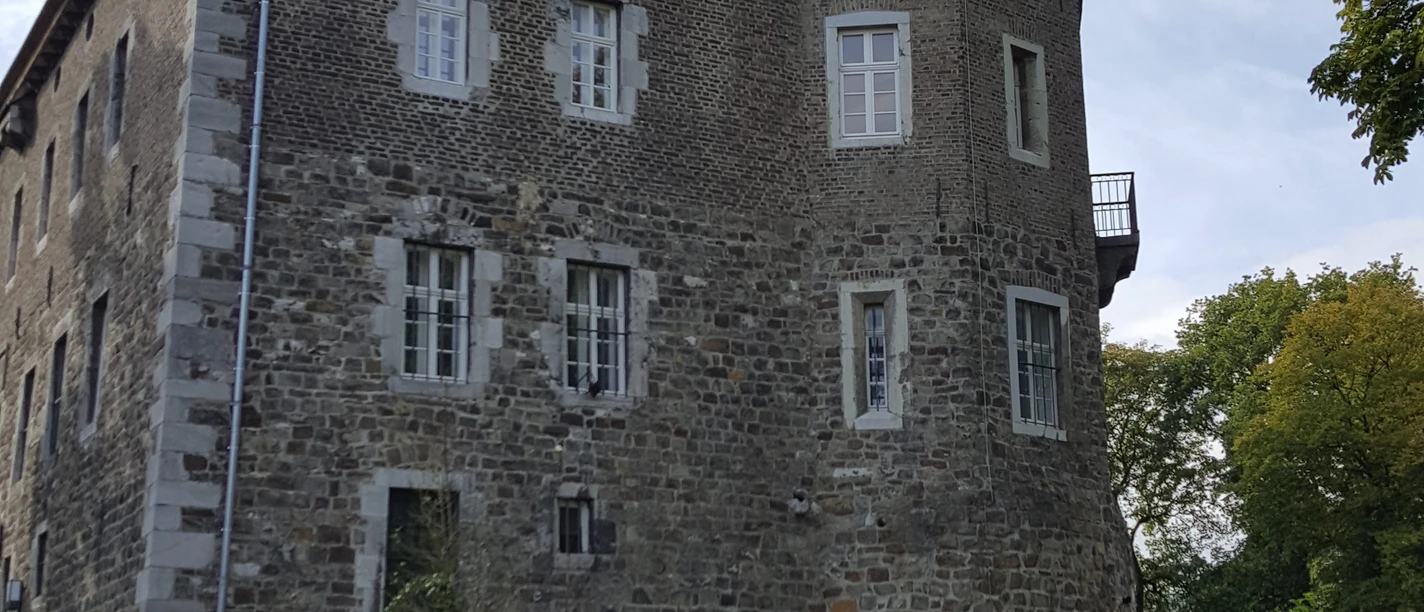 Burg Frankenberg (c)ats Steinhauer Kompaktes Bauwerk mit markanten Zinnen und aus Stein. Es liegt eingebettet in eine grüne Umgebung von Bäumen.