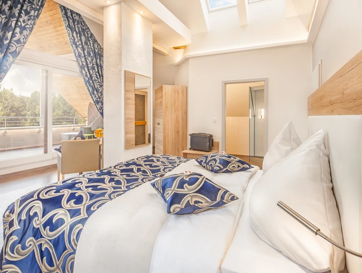 Geräumige Suite mit eleganter Einrichtung, stilvollen blauen Akzenten und Zugang zu einem Balkon.