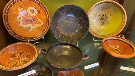 Exponate Töpfereimuseum.jpg Verschiedenfarbige antike Keramikteller und Schalen mit Mustern und Verzierungen.