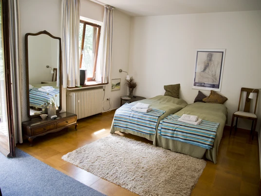 Bed und Breakfast Philosphenweg Zimmer.JPG Ein helles Doppelzimmer mit zwei Einzelbetten, Fenster mit Tageslicht, Spiegel und Holzfußboden.