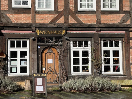 Fachwerkgebäude mit Holzdetails und großer Eingangstür; Fassadenschild lautet „Weinhaus“.
