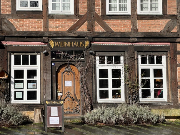 Half-timbered building with wooden details and large entrance door; façade sign reads "Weinhaus".