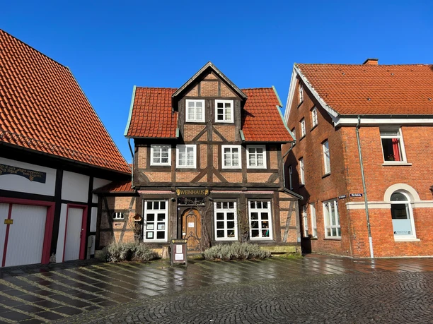 Weinhaus Nienburg Fachwerkhaus mit rotem Ziegeldach, historische Architektur zwischen zwei modernen Backsteinhäusern.