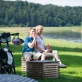 Picknick an der Weser Ein Paar genießt ein Picknick am Flussufer der Weser, umgeben von grüner Natur und Fahrrädern.