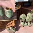 Keramikwerkstatt Luchtmann Verschiedene handgefertigte Keramikvasen und Objekte mit grüner Glasur und floralen Verzierungen.
