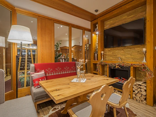 Augustusberg - Hotel & Restaurant Gemütlicher Raum mit Holzmöbeln, rotem Sofa, Kamin und Dekorationen; warme Beleuchtung und einladende Atmosphäre.Cozy room with wooden furniture, red sofa, fireplace and decorations; warm lighting and inviting atmosphere.Útulný pokoj s dřevěným nábytkem, červenou pohovkou, krbem a dekoracemi; teplé osvětlení a příjemná atmosféra.Przytulny pokój z drewnianymi meblami, czerwoną sofą, kominkiem i dekoracjami; ciepłe oświetlenie i zachęcająca atmosfera.Gezellige kamer met houten meubels, rode bank, open haard en decoraties; warme verlichting en uitnodigende sfeer.Camera accogliente con mobili in legno, divano rosso, camino e decorazioni; illuminazione calda e atmosfera invitante.