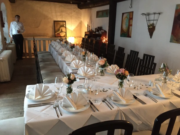 Ein festlich gedeckter langer Tisch mit weißer Tischdecke und Blumenarrangements in einem Restaurant.