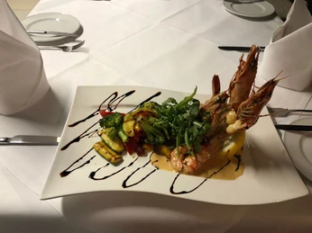 La Scala Essen Homepage.jpg Gegrillte Garnelen auf Gemüsebeet, garniert mit Rucola und Balsamico auf elegantem weißen Teller.