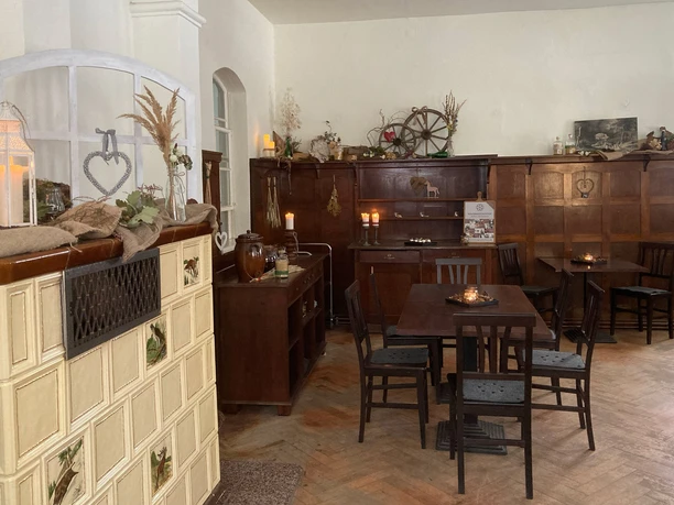 Cozy room with wooden furniture, a tiled stove, candles and decorations; warm, inviting atmosphere.