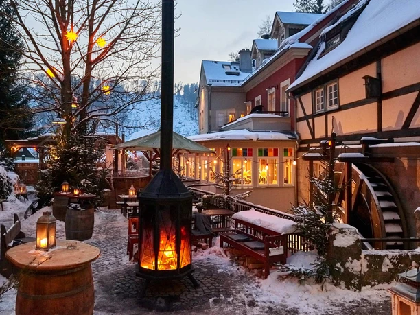 Mühlenhof im Winterdorf Schmilka Verschneiter Hof mit Fachwerkhäusern, beleuchteten Laternen und einem Kaminfeuer; gemütliche, winterliche Atmosphäre.