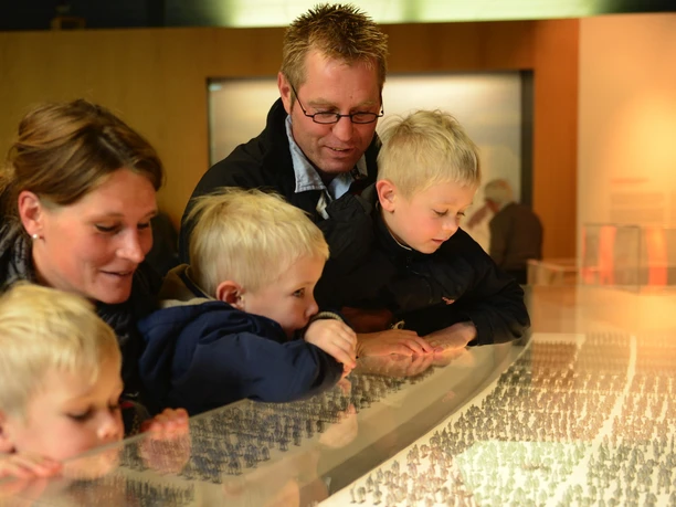 25_jahre_kalkriese.jpg Eine Familie blickt mit Begeisterung auf eine Ausstellung im Museum Kalkriese.