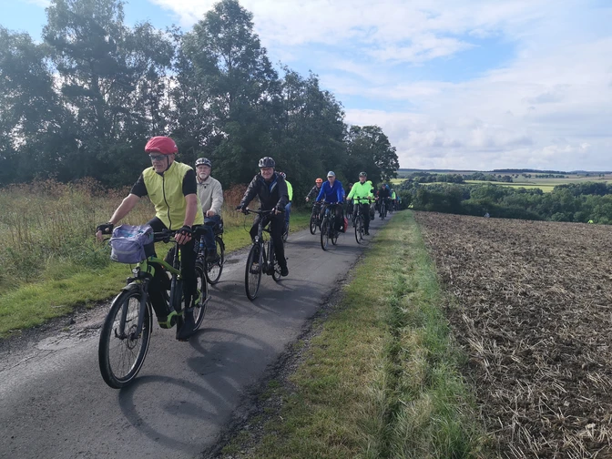 IMG_20210828_100354 Bier-Route-Kreis Höxter.jpg Eine Gruppe von Radfahrern in bunter Sportkleidung fährt auf einem schmalen, bewaldeten Weg.
