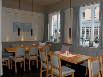 Hotel Vogt_Gastraum Gemütlicher Gastraum mit Holztischen, grauen Polsterbänken und neutralen Farbtonen.