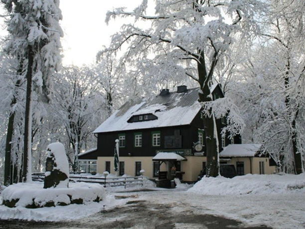 Excursie restaurant op de Ungerberg Besneeuwd gebouw in het bos, omringd door besneeuwde bomen, met een vredige wintersfeer.