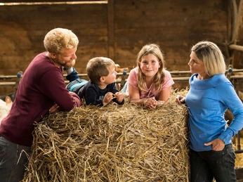Familie mit Kindern auf einem Strohballen Familienbauernhof Fass Familie mit Kindern auf einem Strohballen Familienbauernhof Fass