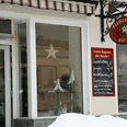 Eingang einer Fleischerei mit rotem Schild und Wochenangebot auf einer Tafel; Fenster mit Stern- und Tannenbaumdekoration, Schnee im Vordergrund.Entrance to a butcher's shop with red sign and weekly specials on a blackboard; window with star and Christmas tree decorations, snow in the foreground.Vchod do řeznictví s červeným nápisem a týdenními nabídkami na tabuli; výloha s hvězdou a ozdobami vánočního stromku, v popředí sníh.Wejście do sklepu mięsnego z czerwonym szyldem i cotygodniowymi promocjami na tablicy; okno z gwiazdą i dekoracjami choinkowymi, śnieg na pierwszym planie.Ingang van een slagerij met rood bord en wekelijkse specials op een schoolbord; raam met ster en kerstboomversiering, sneeuw op de voorgrond.Ingresso di una macelleria con insegna rossa e specialità settimanali su una lavagna; vetrina con stelle e decorazioni per l'albero di Natale, neve in primo piano.