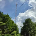 Teutoburger Wald / Detmold / Bielstein Ein hoher Sendemast ragt über grüne Baumwipfel, umgeben von blauem Himmel und weißen Wolken.
