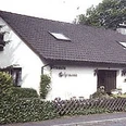 Pension_Gehrmann.jpg.png Ein weißes, einstöckiges Landhaus mit Satteldach, umgeben von grünem Buschwerk und Holzzaun.