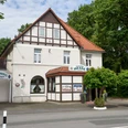 Fachwerkhaus mit Restaurant Hesse, Eingangsbereich mit begrünten Blumenkübeln, umgeben von Bäumen.