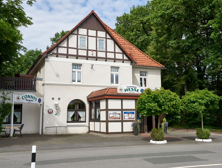 Fachwerkhaus mit Restaurant Hesse, Eingangsbereich mit begrünten Blumenkübeln, umgeben von Bäumen.