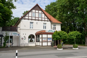 Gaststätte Hesse_Außenansicht Fachwerkhaus mit Restaurant Hesse, Eingangsbereich mit begrünten Blumenkübeln, umgeben von Bäumen.