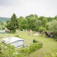 Campingplatz Eggewald in Horn-Bad Meinberg Grüner Campingplatz mit Zelten und Wohnwagen, umgeben von Bäumen, mit Spielplatz im Hintergrund.