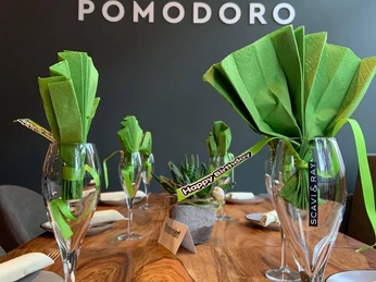 Ein stilvoll gedeckter Tisch in der Osteria Pomodoro mit grünen Servietten und Namenskärtchen.
