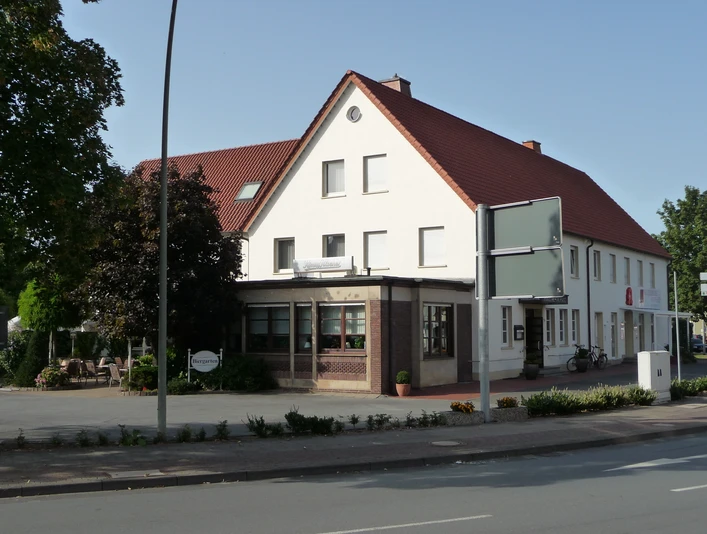 Hotel Zur Post_Außenansicht Zweistöckiges Gasthaus mit weißen Wänden, rotem Ziegeldach und umliegenden Bäumen an einer Straße.