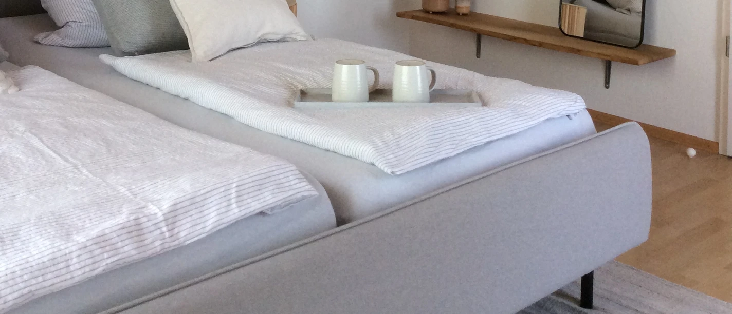 bed 'n' breakfast_Zimmer Modernes Schlafzimmer mit einem Doppelbett, helle Stoffe, Wandspiegel und Holzdecke sorgen für Gemütlichkeit.