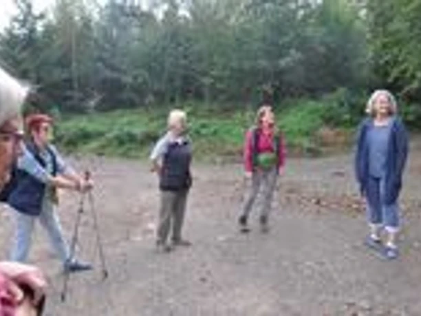 DSC_9449.JPG Fünf Personen im Outdoor-Outfit stehen lachend in einer Waldlichtung, umgeben von Bäumen.