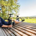 Waldsofa an der "Schönen Aussicht" bei Heckhaus Ein lächelnder Radfahrer sitzt auf einer Holzbank, genießt die Aussicht auf eine grüne Landschaft.