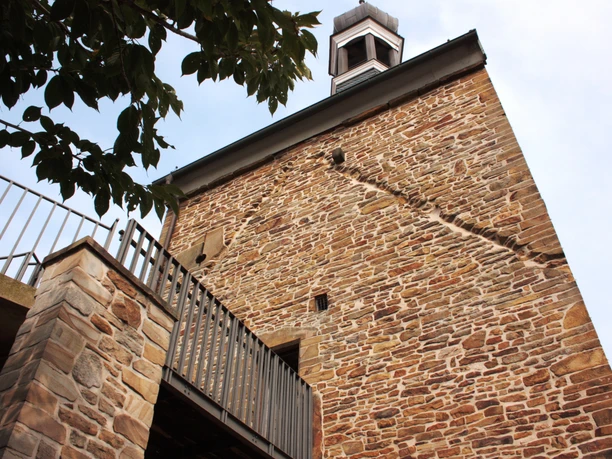 Hohe Pforte.jpg Steinerner Turm mit Glocke, seitliche Metalltreppe, Baumblätter am oberen Rand.