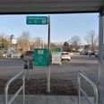 Ladestation am Rathaus mit Blick auf die Bürmsche Wiese Parkplatz mit E-Bike-Ladestation, umgeben von kahlen Bäumen und einem Kirchturm im Hintergrund.