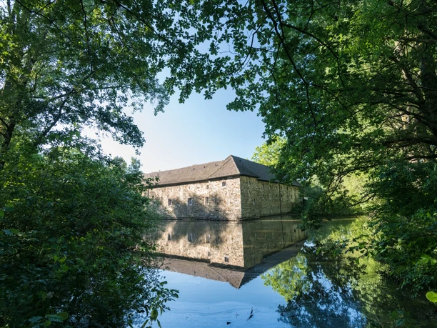 Wasserburg Haus Graven in Langenfeld Wasserburg Haus Graven in Langenfeld: Umgeben von Wassergraben, Bäumen und historischer Architektur.