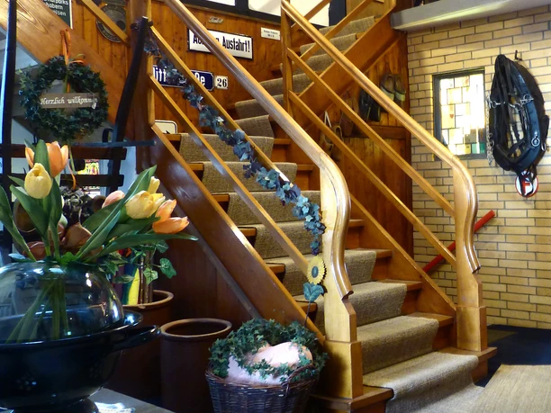 Foto Deele mit Treppe.jpg Eine hölzerne Treppe mit verzierten Handläufen in einem rustikalen, liebevoll dekorierten Innenraum.