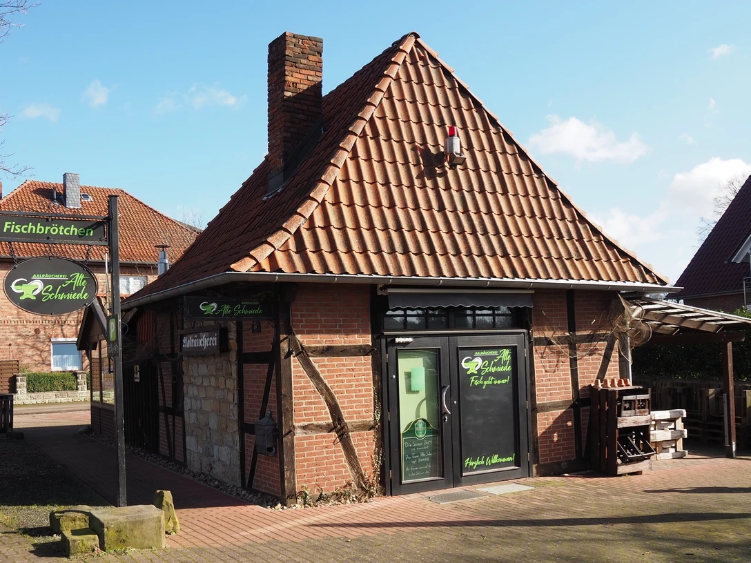 Alte Schmiede Ein traditionelles Fachwerkgebäude mit rotem Ziegeldach und grünen Schildern einer Schmiede.A traditional half-timbered building with a red tiled roof and green forge signs.En traditionel bindingsværksbygning med rødt tegltag og grønne smedjeskilte.Een traditioneel vakwerkgebouw met een rood pannendak en groene smidstekens.