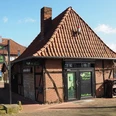 Alte Schmiede Ein traditionelles Fachwerkgebäude mit rotem Ziegeldach und grünen Schildern einer Schmiede.A traditional half-timbered building with a red tiled roof and green forge signs.En traditionel bindingsværksbygning med rødt tegltag og grønne smedjeskilte.Een traditioneel vakwerkgebouw met een rood pannendak en groene smidstekens.