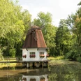 Heidberger Mühle im Ittertal bei Haan Historische Windmühle im Grünen, umgeben von Bäumen, mit einem kleinen Teich im Vordergrund.