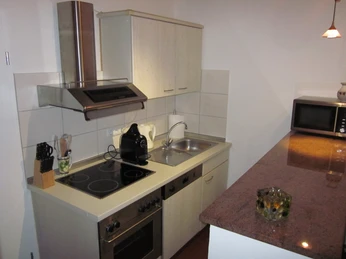 Appartement_Jainek 2.JPG Kompakte Küche mit Elektroherd, Spüle, Kaffeemaschine und Mikrowelle, daneben eine Arbeitsplatte.