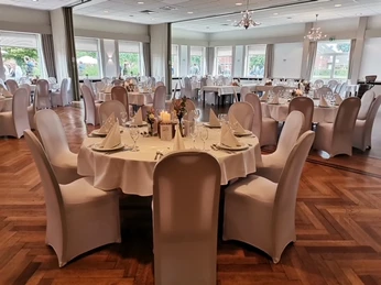 Zum Doppe_Festsaal Elegant gedeckter Festsaal mit runden Tischen, weißen Stühlen und dekorativen Fenstern auf Park.